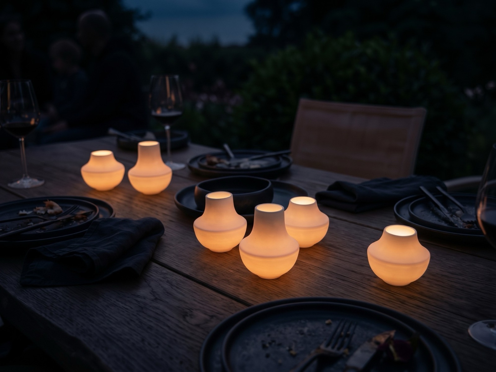 casting: Windlichter auf einem gedeckten Gartentisch am Abend